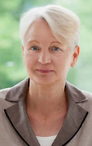 Eine Frau steht draußen und prüft sorgfältig Arbeitsunterlagen, bereit für den nächsten handwerklichen Schritt.